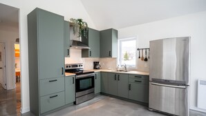 Una cocina moderna con un refrigerador de acero inoxidable, un horno empotrado y una estufa.