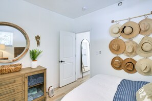 Ein Schlafzimmer mit Bett, Kommode, Spiegel und einem Wandhaken für Hüte.