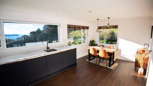 Eine moderne Küche mit großem Fenster, dunklem Holzboden und einem Essbereich mit Holztisch und Stühlen.