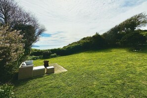 A grassy outdoor area with a seating arrangement and a view of the sea.