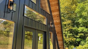 A modern building with large windows, a wooden deck, and outdoor seating. - Tranquil retreat nestled in the breathtaking landscape of Hocking Hills. (McArthur)