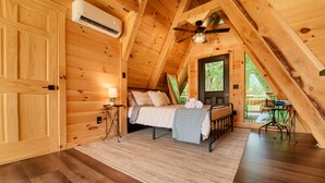 A cozy attic bedroom with a bed, a ceiling fan, and a view of the outdoors. - Tranquil retreat nestled in the breathtaking landscape of Hocking Hills. (McArthur)