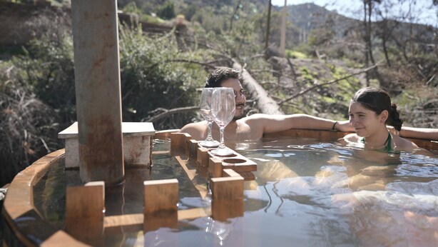 A hot tub with wooden blocks, surrounded by natural landscape and hills. - Refugio Atreyu (Lo Barnechea)