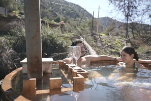 A hot tub with wooden blocks, surrounded by natural landscape and hills. - Refugio Atreyu (Lo Barnechea)