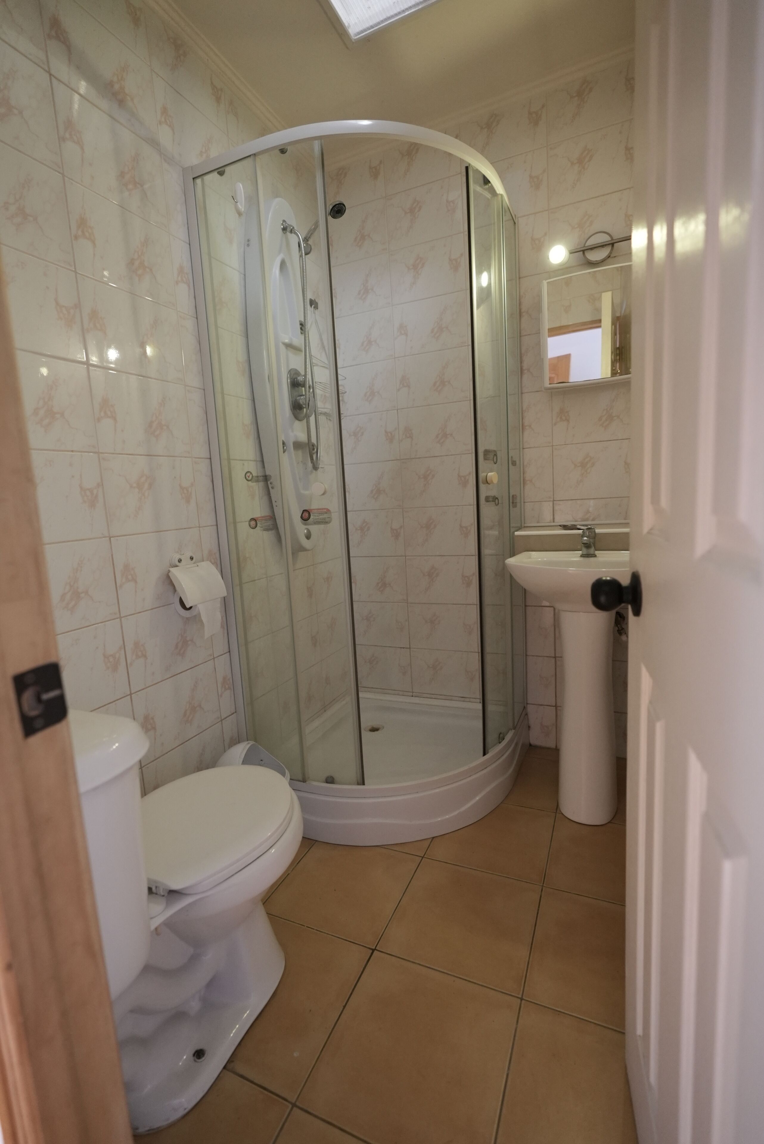 A bathroom with a glass-enclosed shower, a toilet, and a sink.