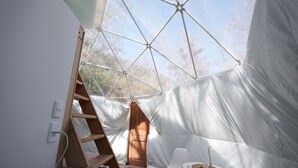 A tent with a wooden ladder, a white chair, and a small table with a vase. - Refugio Atreyu (Lo Barnechea)