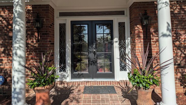 A brick building with a white porch, two potted plants, and a black door with glass panels. - Beautiful and Scenic 6 bedrooms and 6 bathrooms large pool a hot tub 7000sqft (Prospect)