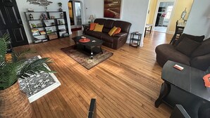 A living room with a brown leather sofa, a coffee table, and a bookshelf. - 6 Block to oceanfront and in the center of the vibe district! (Virginia Beach)