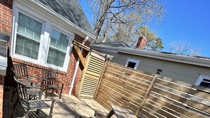 A wooden deck with picnic tables and chairs, a wooden fence, and a brick house in the background. - 6 Block to oceanfront and in the center of the vibe district! (Virginia Beach)