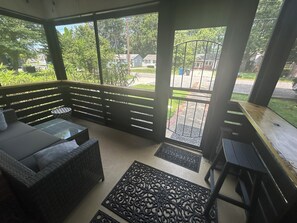 An enclosed porch with a sofa, a small table, and a bench.