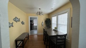 A dining area with a wooden bench, a table with chairs, and decorative fish wall art. - 6 Block to oceanfront and in the center of the vibe district! (Virginia Beach)
