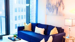 A modern living room with a blue sofa, a small table with a plant, and a lamp.