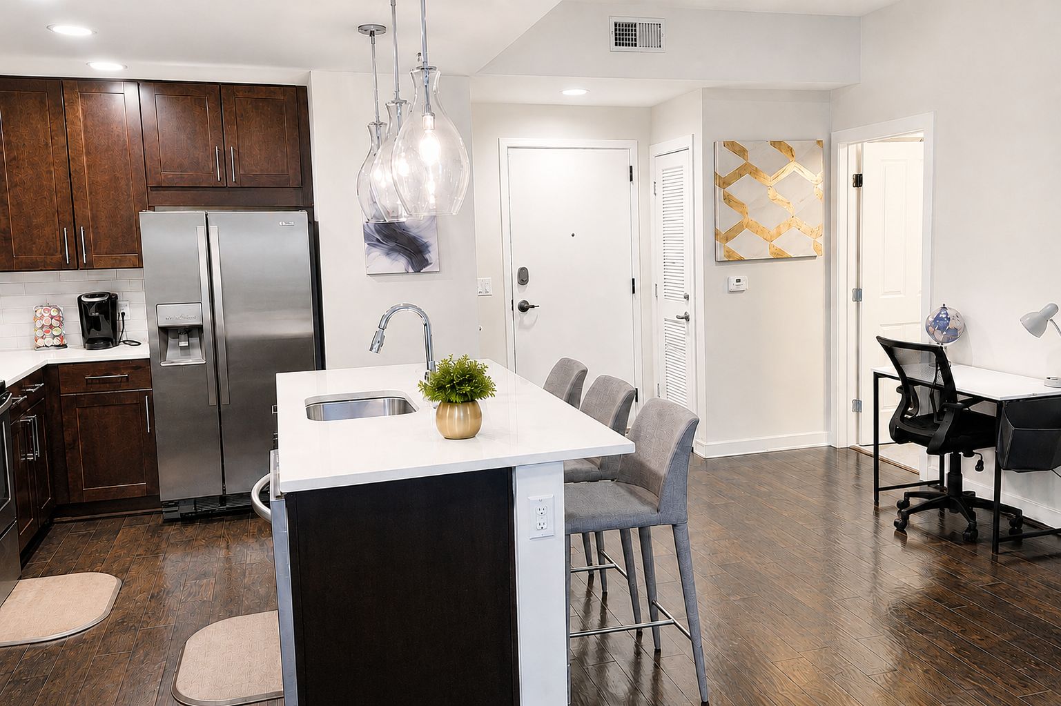 A modern kitchen with a central island, stainless steel appliances, and a dining area with a white table and grey chairs.