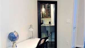 A small office space with a desk, chair, globe, and lamp.