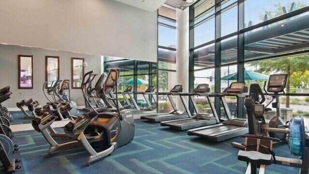 A modern gym with treadmills, elliptical machines, and stationary bikes.