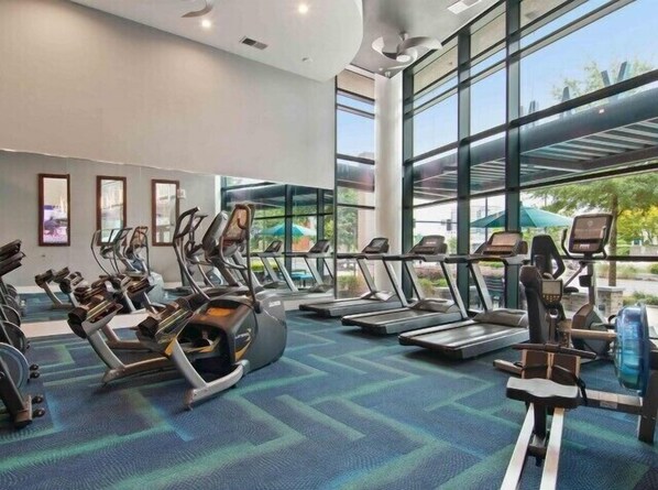 A modern gym with treadmills, elliptical machines, and stationary bikes. - Blue Luxe | Balcony View | Pool | Modern Amenities (Atlanta)