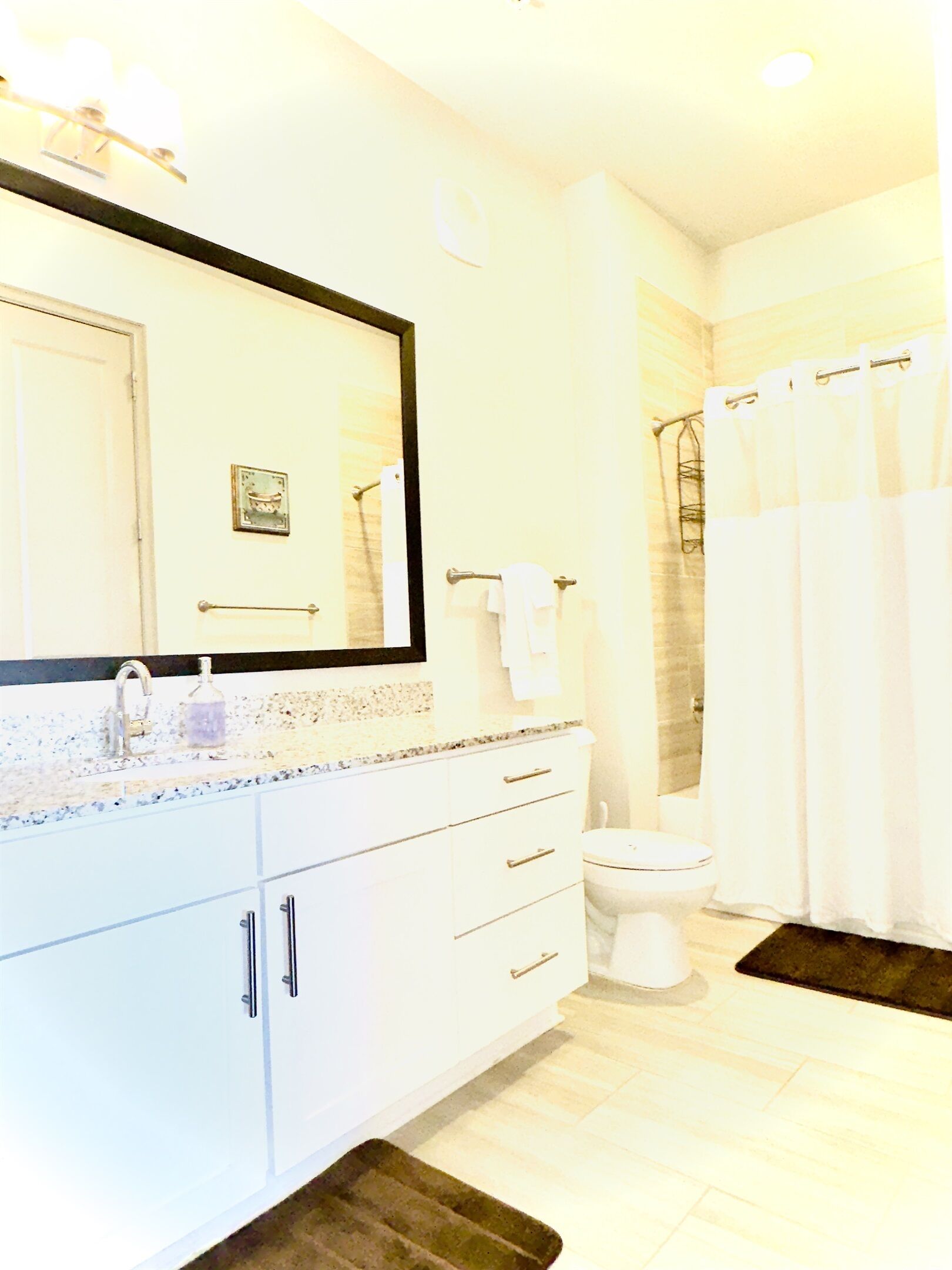 A bathroom with a sink, mirror, toilet, and shower curtain.