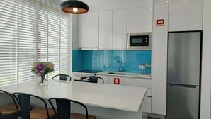 A modern kitchen with white cabinets, a blue backsplash, a stainless steel refrigerator, and a pendant light. - AL.Fredos 2| Mindelo | Beachfront (Mindelo)