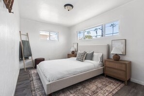 A bedroom with a bed, nightstands, a lamp, a ladder, and a window.