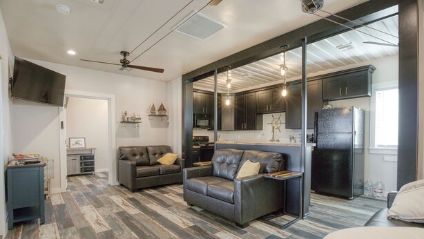 A modern living room with a fireplace, leather sofas, and a large window. - Camp Conex a Shipping Container in Shell Beach, LA (St. Bernard Parish)