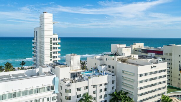A coastal hotel with multiple floors, a rooftop pool area, and ocean views.