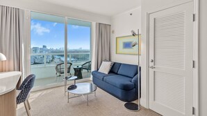 A modern hotel room with a balcony, a sofa, a small table, and a chair.