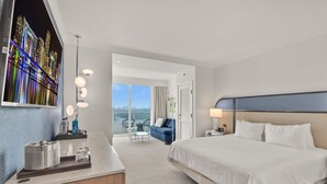 A hotel room with a large bed, a desk with a mirror, and a view of the cityscape.