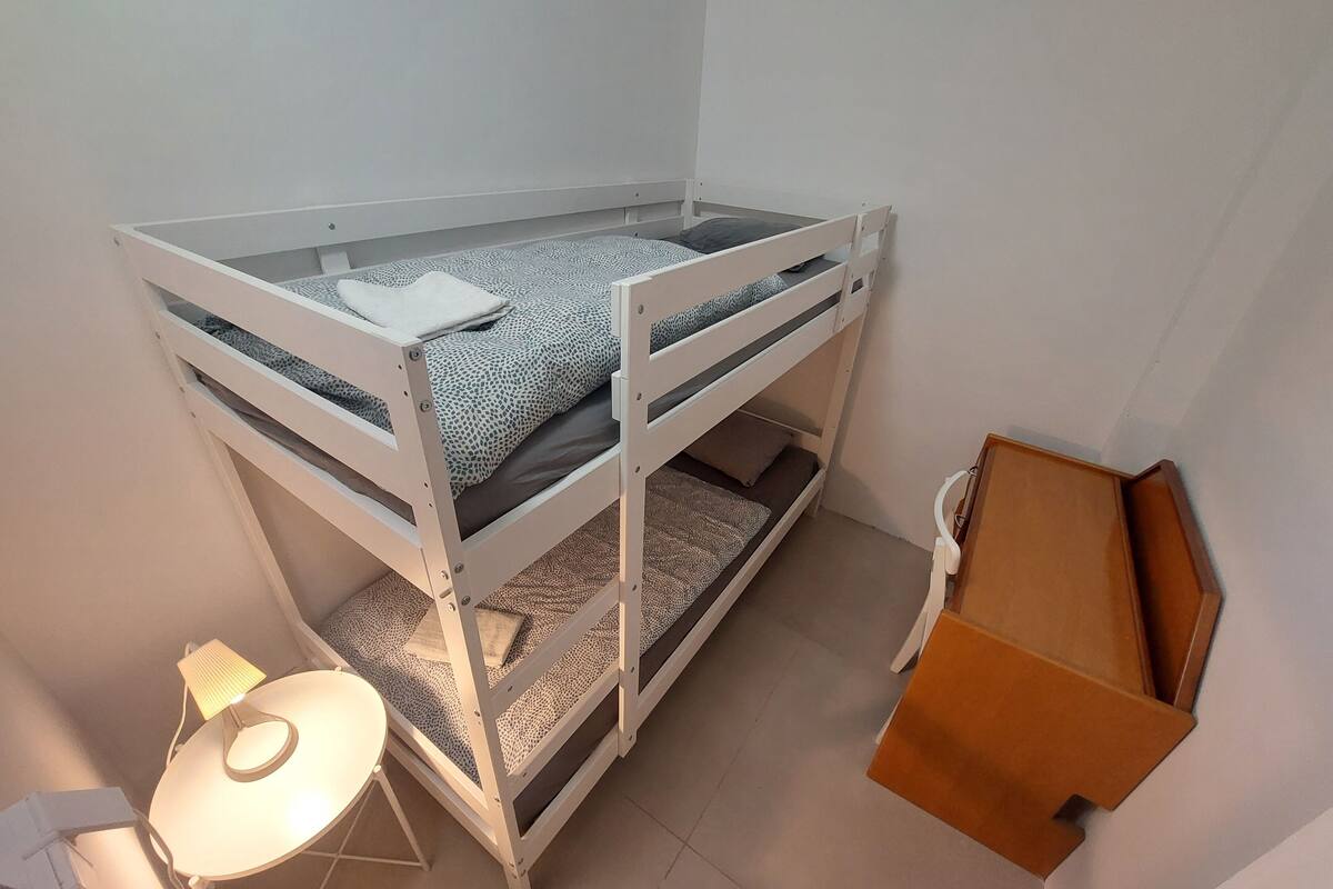 A bunk bed with a desk and chair, a lamp, and a cardboard box.
