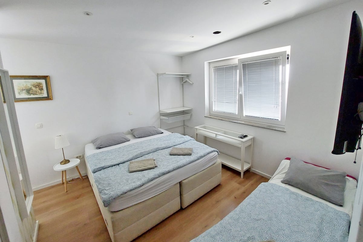 A bedroom with a bed, a desk, and a window.