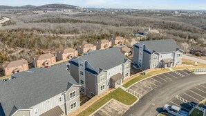 A residential area with modern two-story houses, a parking lot, and a distant view of a town with a church. - Branson Beauty! 4brm condo! Central Location (Branson)