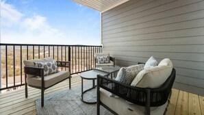 A balcony with a sofa, chairs, and a table, overlooking a desert landscape. - Branson Beauty! 4brm condo! Central Location (Branson)