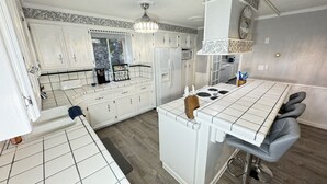 A kitchen with white cabinets, a tiled backsplash, a built-in oven, and a bar area with stools.