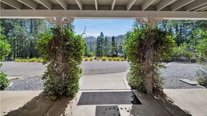 A covered walkway with a view of a landscaped area and distant mountains.