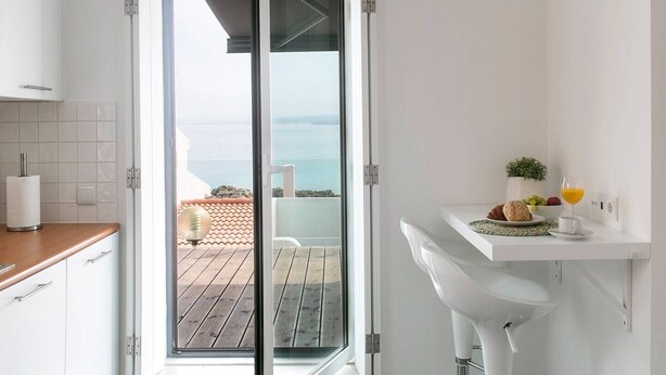 Une cuisine moderne avec une porte-fenêtre coulissante donnant sur un balcon avec vue sur la mer.
