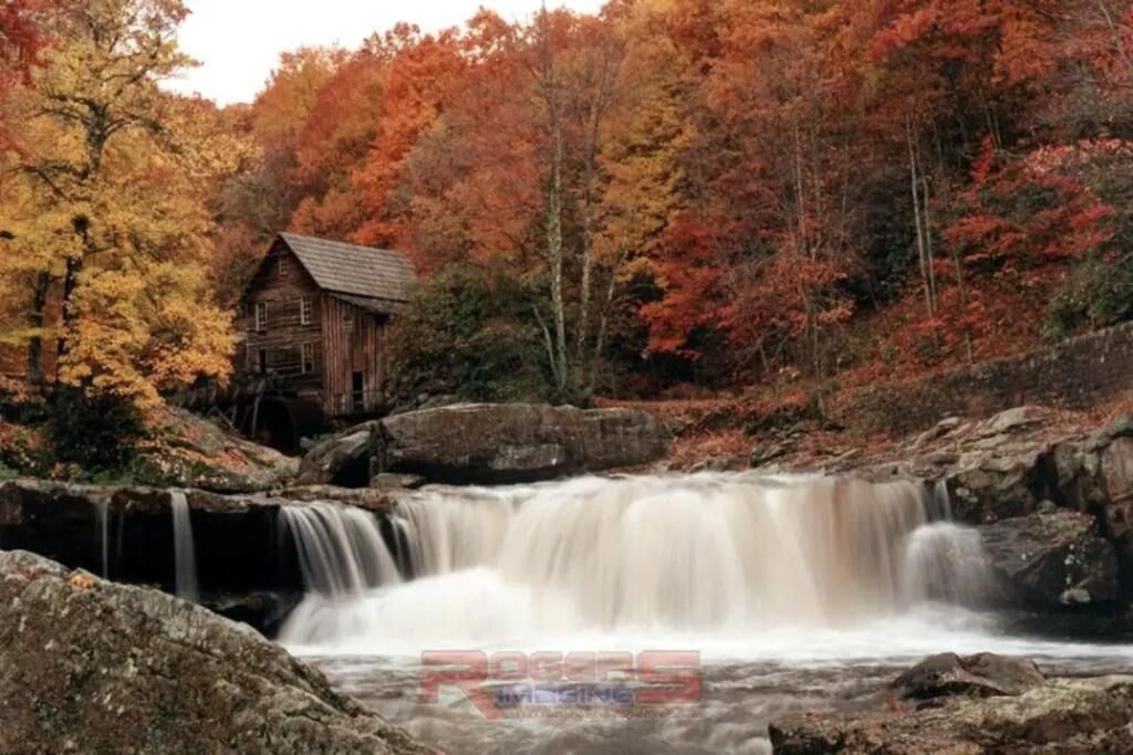Eine rustikale Holzhütte, umgeben von Herbstlaub und einem Wasserfall.