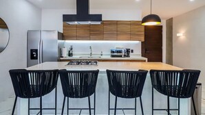 A modern kitchen with a central island, black chairs, and wooden cabinets.