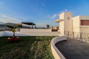Enjoy panoramic views of the city and mountains from this rooftop terrace with a covered seating area and a lush palm tree.