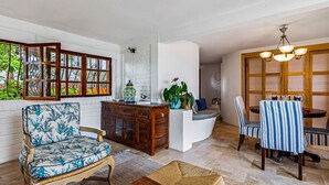 Een woonkamer met een bank, een eettafel met stoelen, een kast en een decoratieve wand met een raam.