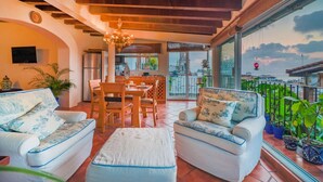 A spacious living area with a balcony, furnished with sofas and a dining table. - Studio La Vista – Stunning Views in the Heart of Puerto Vallarta (Puerto Vallarta)