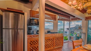 A kitchen with a stainless steel refrigerator, a wooden island with a lattice design, and a dining area with a table and chairs. - Studio La Vista – Stunning Views in the Heart of Puerto Vallarta (Puerto Vallarta)