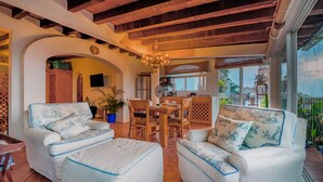 A cozy living room with white sofas and a dining table, a kitchen in the background, and a balcony with a view. - Studio La Vista – Stunning Views in the Heart of Puerto Vallarta (Puerto Vallarta)