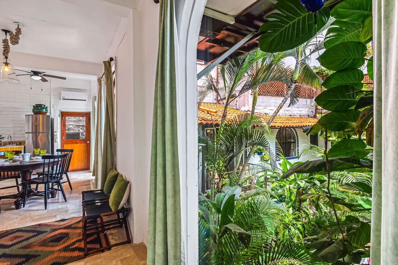 Ein geräumiges Zimmer mit Essbereich, Deckenventilator und Blick auf einen üppigen Garten durch ein Fenster.