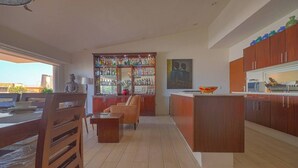 A modern kitchen with wooden cabinets, a central island, and a bar area with a variety of bottles.