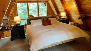 Een gezellige slaapkamer met houten lambrisering, een groot bed, bedlampen en uitzicht op de omgeving door een raam.