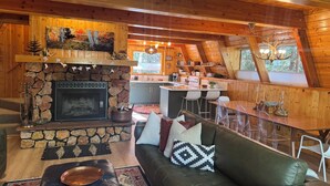 Een gezellig chaletinterieur met een stenen open haard, een eethoek en een keuken.