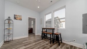 A room with a wooden floor, a desk with two chairs, a metal shelf, and a window. - Just steps away from the Boardwalk & Beaches, Walkable to Entertainment! (North Beach)