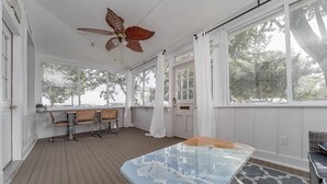 A room with a ceiling fan, a table with a marble top, a patterned rug, and a view of trees through large windows. - Just steps away from the Boardwalk & Beaches, Walkable to Entertainment! (North Beach)