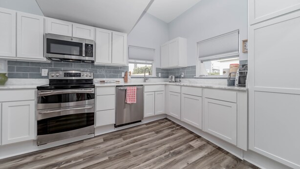 A modern kitchen with white cabinets, a stainless steel oven, a microwave, and a dishwasher. - Just steps away from the Boardwalk & Beaches, Walkable to Entertainment! (North Beach)