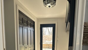 A hallway with a dark wood floor, a door leading outside, and a ceiling light fixture. - Spacious 5-bedroom house in Green Bay with WiFi, 15 minutes to Packer stadium (Green Bay)