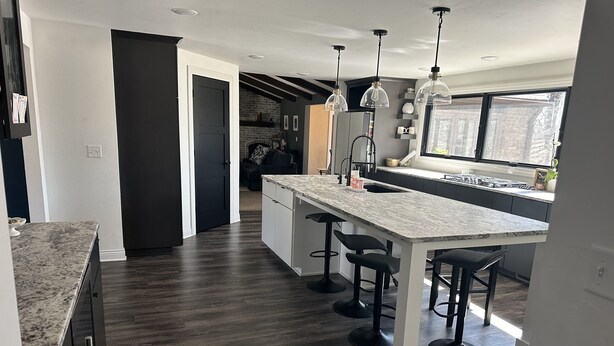 A modern kitchen with a large island, bar stools, pendant lighting, and a view of the outdoors. - Spacious 5-bedroom house in Green Bay with WiFi, 15 minutes to Packer stadium (Green Bay)